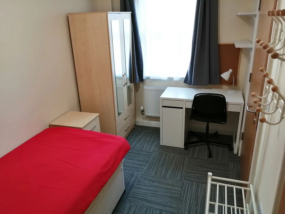 A student bedroom with a desk under the window and fitted storage