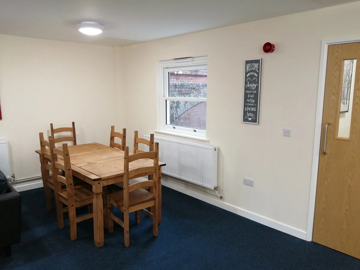 A dining area with a wooden table and chairs beside the kitchen
