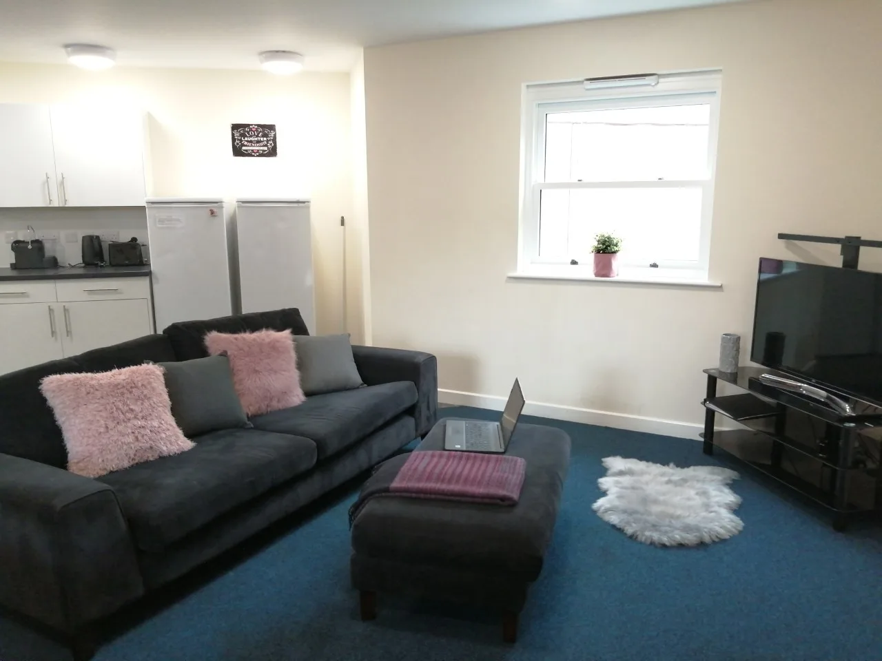 A lounge with a corner sofa and a wall-hung television